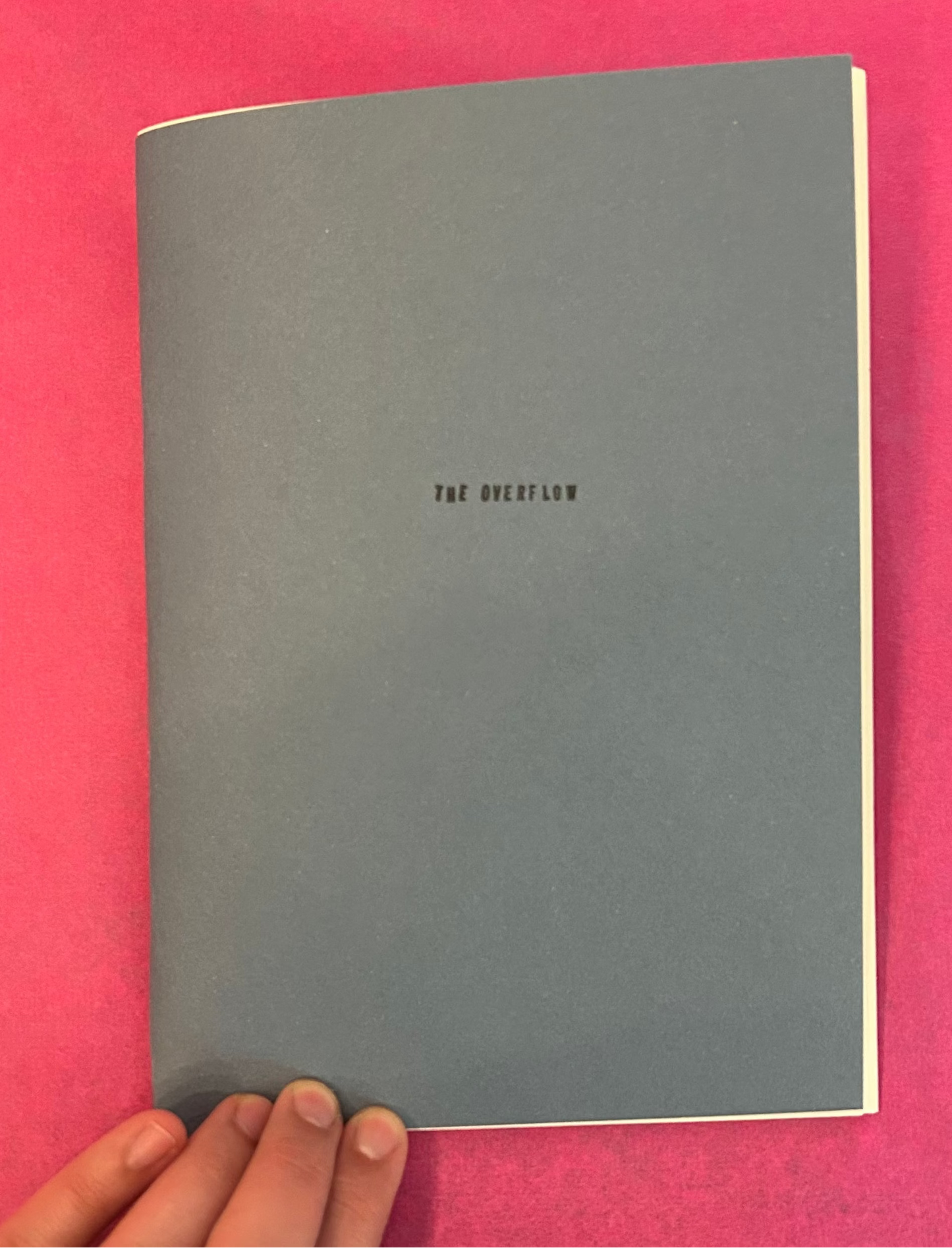 Gray notebook with 'The Overflow' text on a pink background

