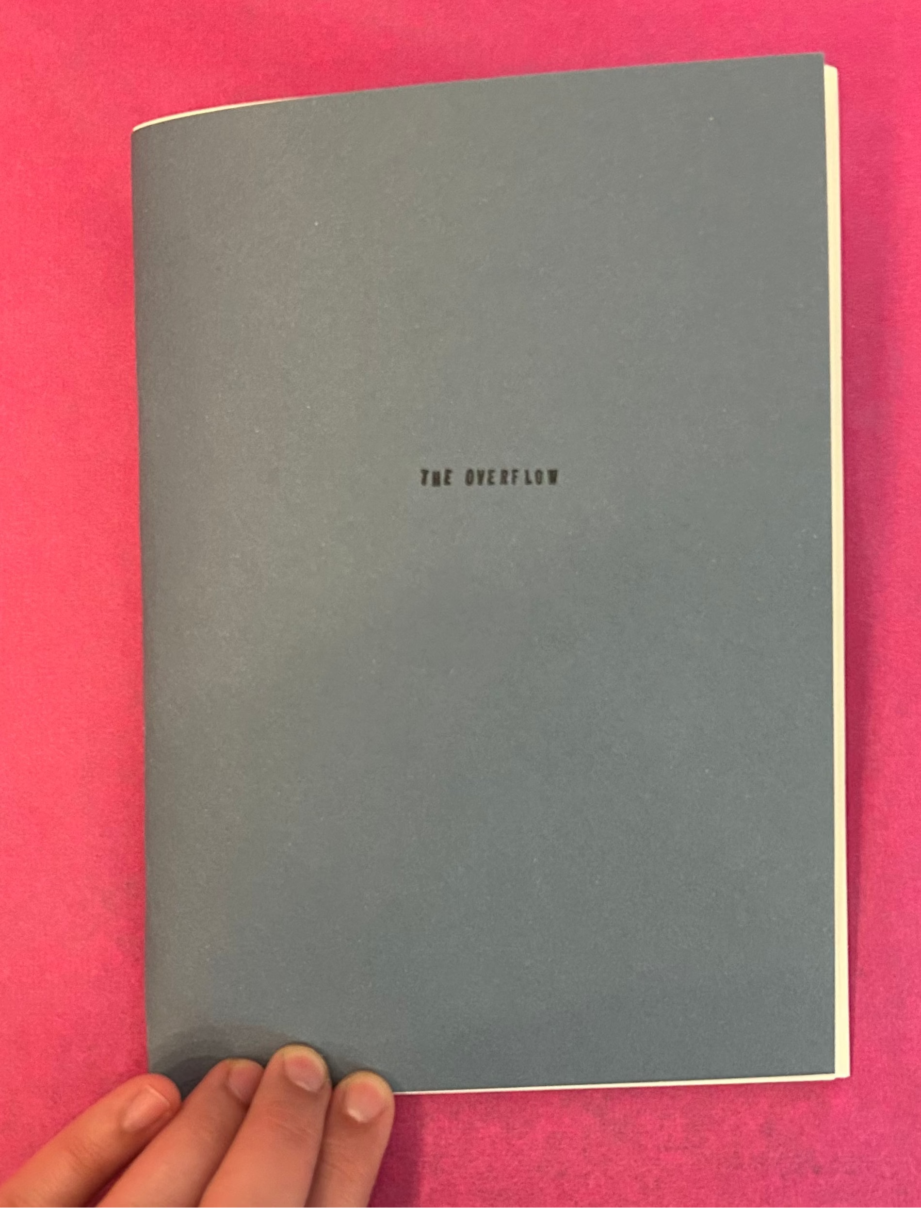 Gray notebook with 'The Overflow' text on a pink background


